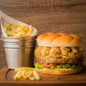 Shop1 Delicious gourmet burger with crispy fried onions and fresh fries served on a wooden platter.