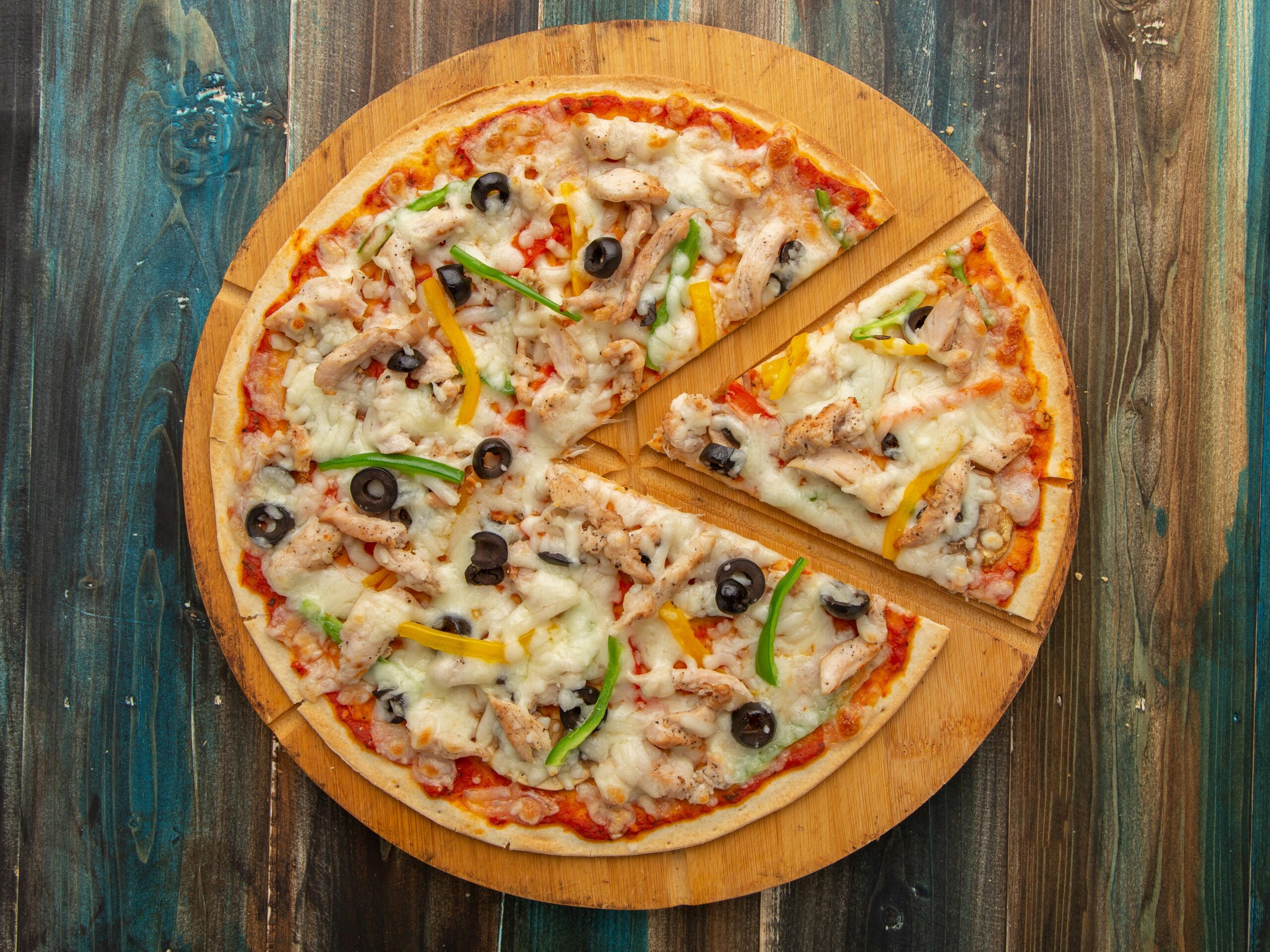 pexels photo 20115307 20115307 Top view of a chicken pizza with olives and bell peppers on a wooden board.