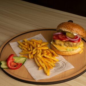 Shop1 Mouthwatering cheeseburger with fries and veggies served on a stylish wooden tray.