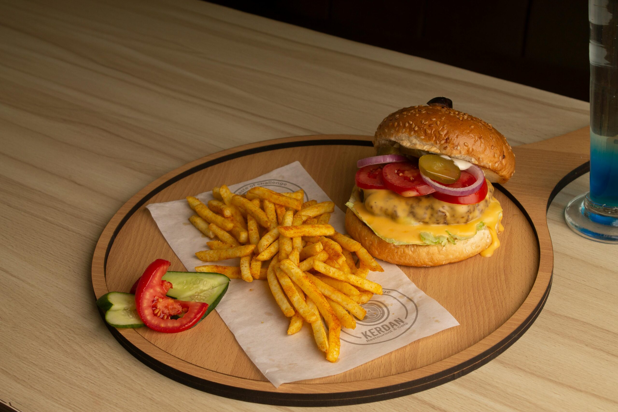 pexels photo 25284276 25284276 Mouthwatering cheeseburger with fries and veggies served on a stylish wooden tray.