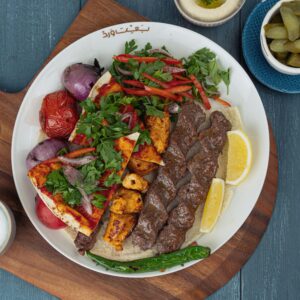 Shop1 Delicious Middle Eastern platter featuring grilled meats, vegetables, and fresh herbs.